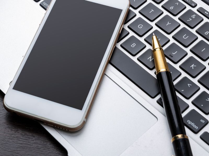 Laptop, telefon i notes na biurku – narzędzia do zarządzania czasem i planowania dnia